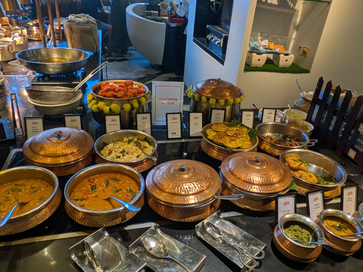 インド系コーナーの銅鍋が並ぶカレーステーション。数種類のカレーが湯気を立てている