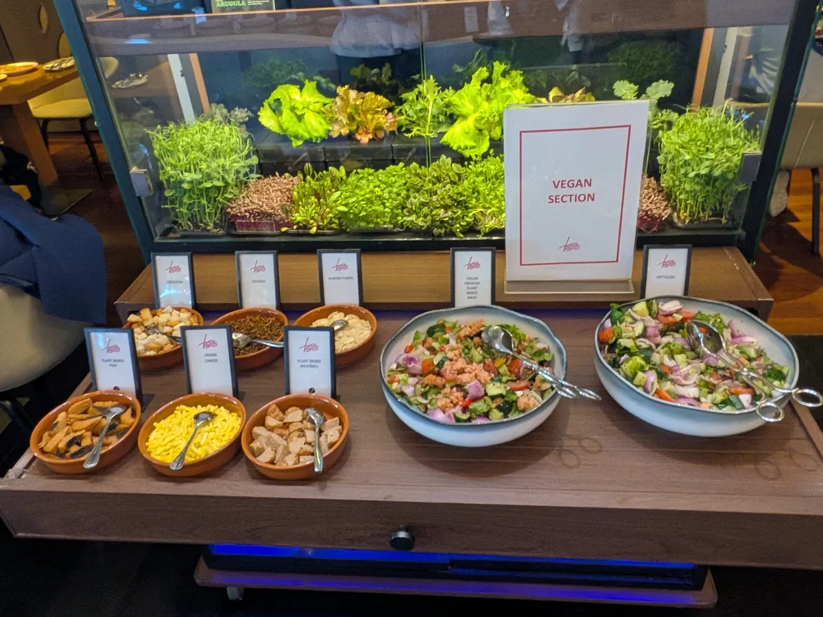 ガラスケースの中で葉物を栽培しているサラダバーと、盛り付けられたサラダ数種