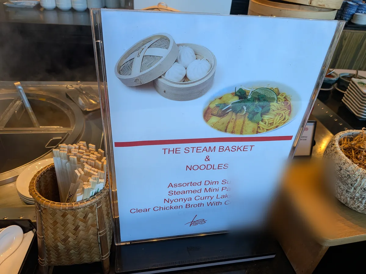 「THE STEAM BASKET & NOODLES」の案内札。点心と麺の実演コーナーのメニューが書かれている