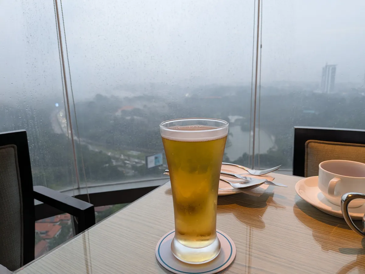 スコールの雨がガラスをつたう33階の窓辺に置かれたビールのグラス