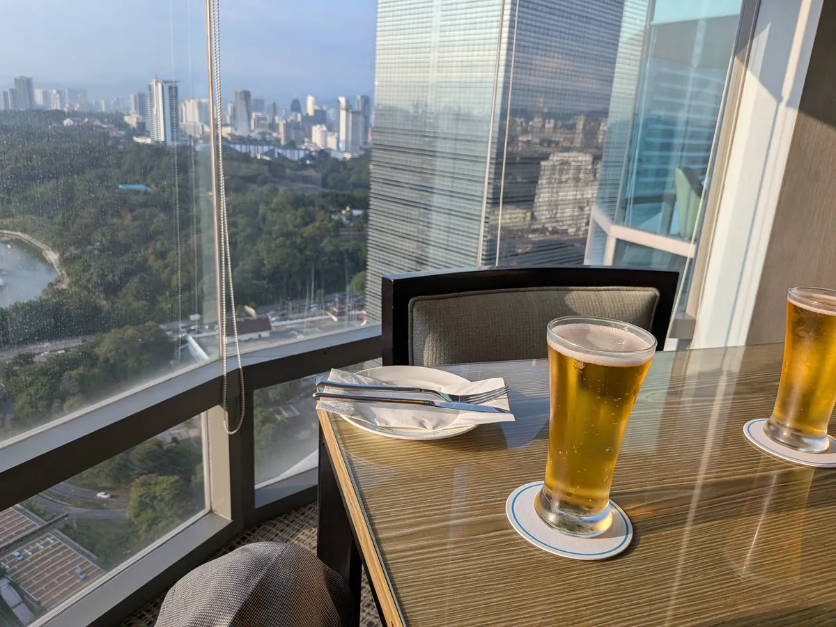 窓辺のテーブルに置かれたビールのグラスと夕暮れの景色