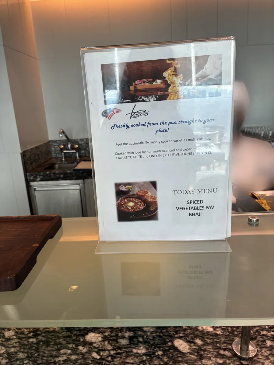 Vasco'sのシェフによるライブ調理の案内札。ONLY IN EXECUTIVE LOUNGE HILTON KLと書かれ、本日のメニューはSPICED VEGETABLES PAV BHAJI