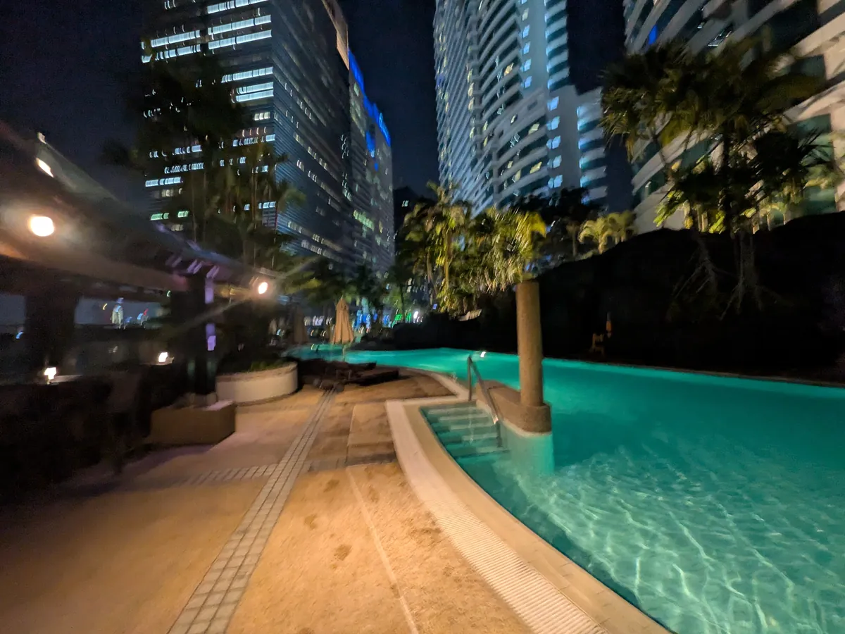 ライトアップされた夜のプールと、ヤシの木のシルエット