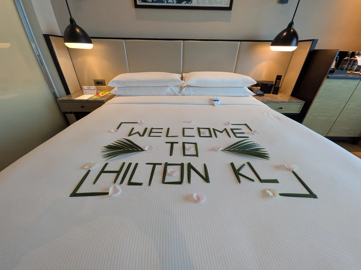 ベッドの上にタオルで組まれた「WELCOME TO HILTON KL」の文字のウェルカム装飾
