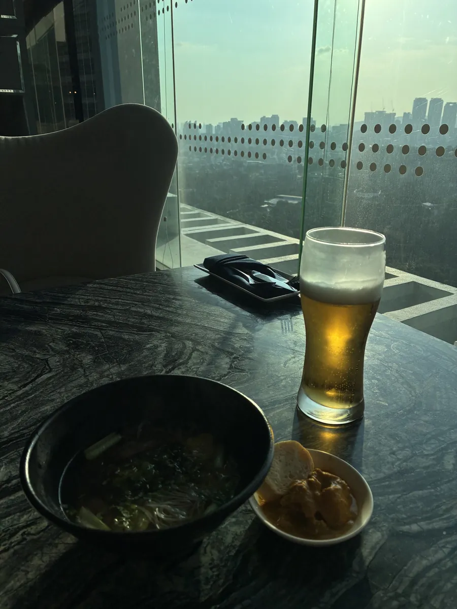 窓際のテーブルに置かれたビールのグラスと小鉢