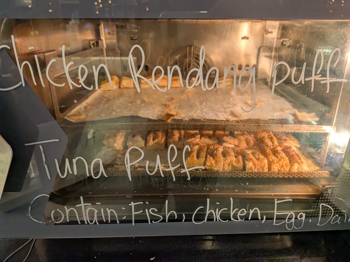 Chicken Rendang PuffとTuna Puffの手書き黒板と、ガラスケースに並ぶパイ