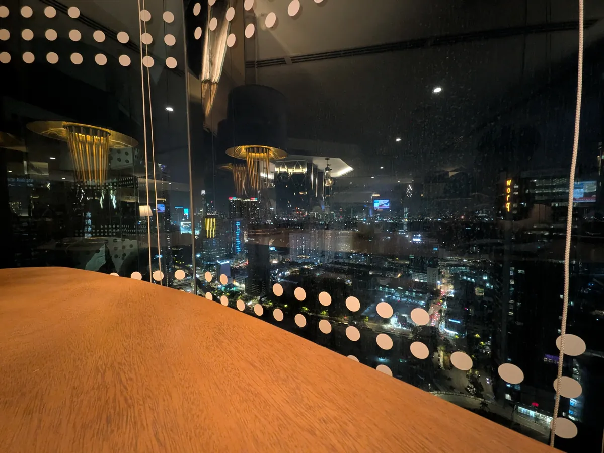 33階の窓から見たクアラルンプールの夜景。木のカウンター越しに街の明かりが広がる