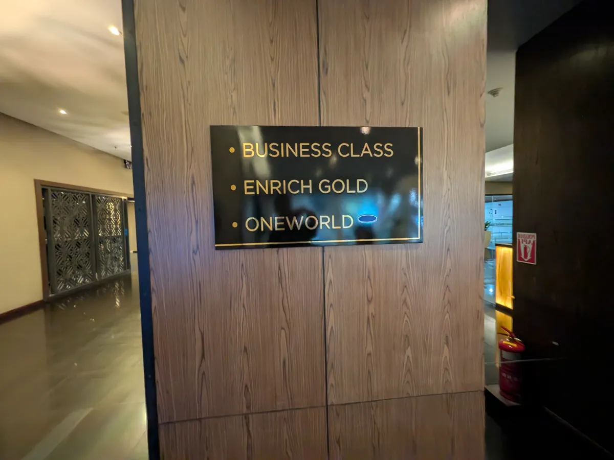 ゴールデンラウンジ Business 側の入口掲示。「BUSINESS CLASS」「ENRICH GOLD」「ONEWORLD」と利用対象が金文字で並ぶ