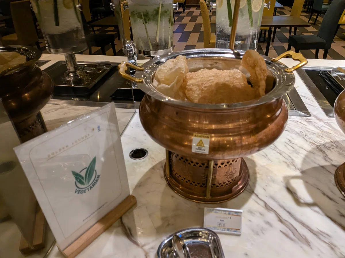 揚げたてのプーリーが入った銅鍋と、その手前に立てられたVEGETARIAN表示のカード