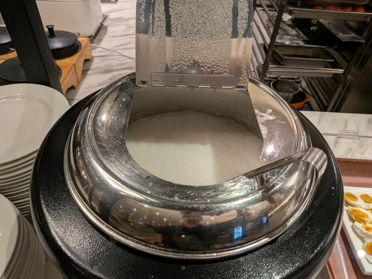 保温器に入った白いお粥。手前には取り皿が積まれている