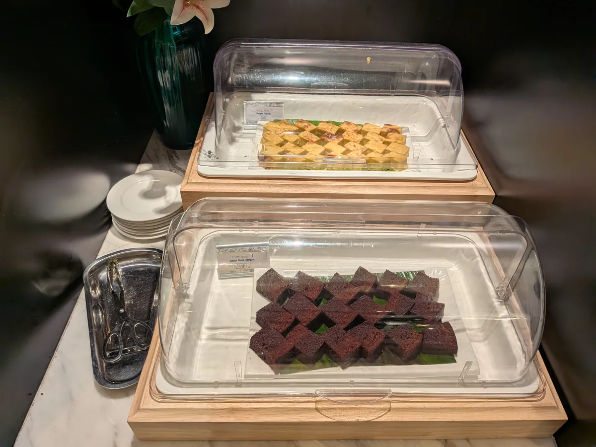 アクリルケースに入ったマレーシアの伝統菓子クエ2種。ココナッツをまぶした茶色のクエと、格子模様の黄色いクエ