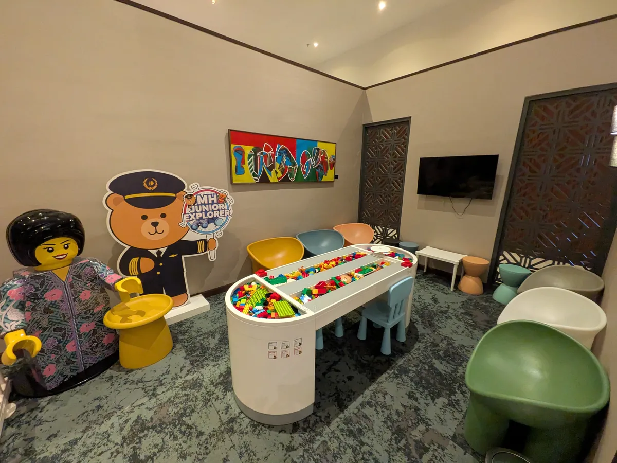 ゴールデンラウンジのキッズスペース全景。LEGOのビルディングテーブル、子ども用の椅子、壁掛けテレビ、カラフルなアートが配置されている