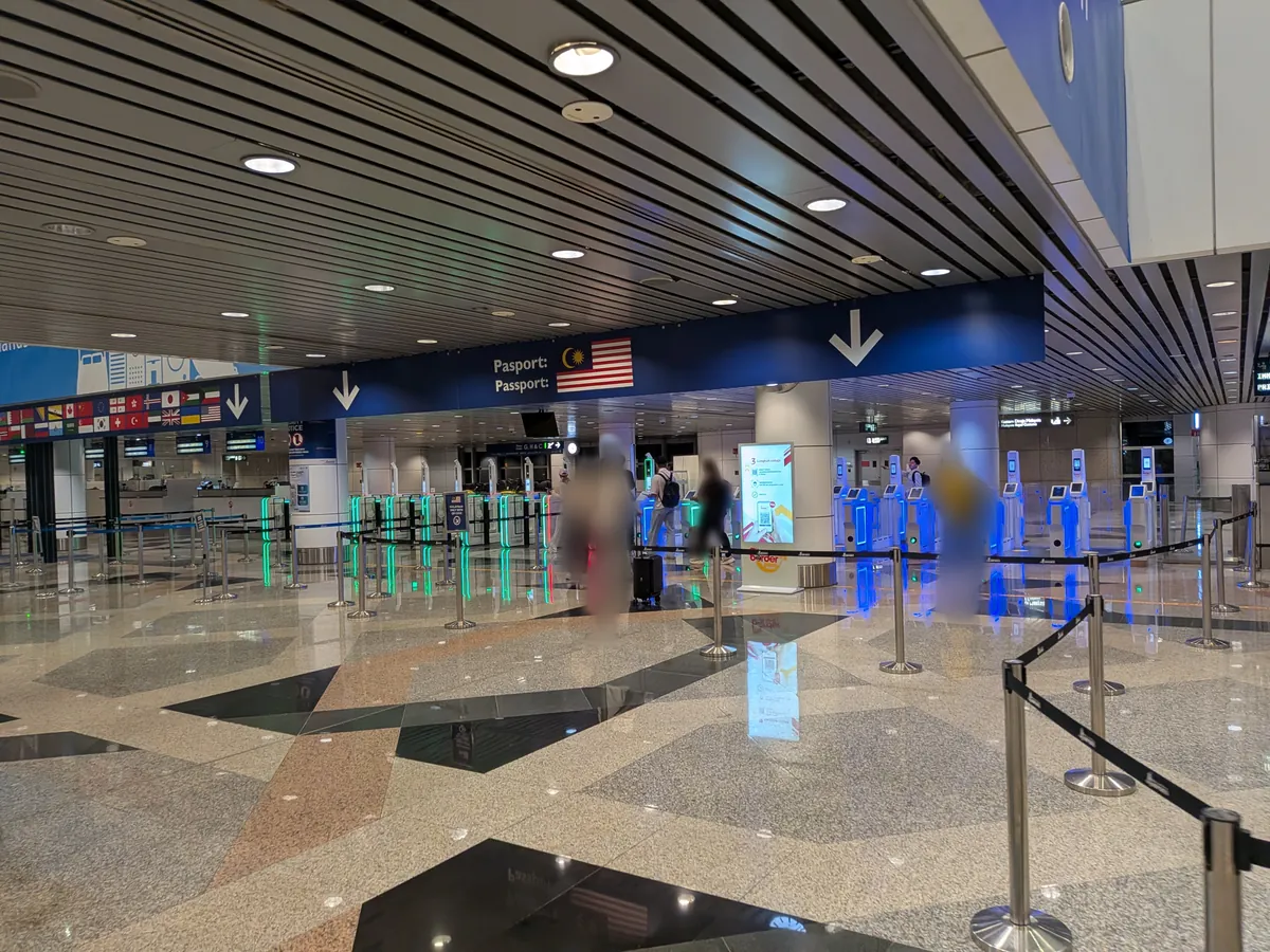 クアラルンプール国際空港第1ターミナルの出国審査エリア。マレーシア国旗と「Pasport / Passport」の案内板の下にオートゲートが並ぶ