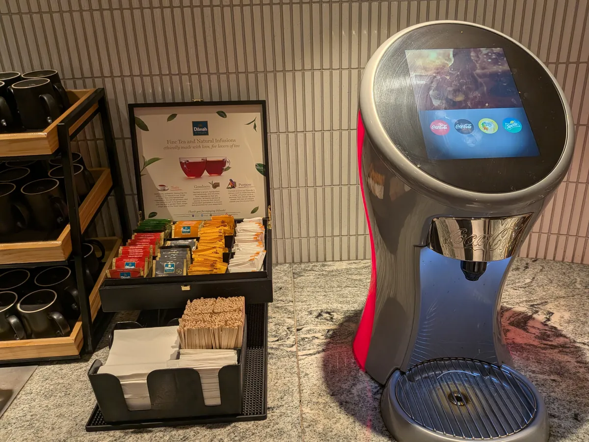 Dilmahの紅茶・ハーブティーのボックスとマドラー、その隣にタッチパネル式のコカ・コーラ ドリンクサーバー
