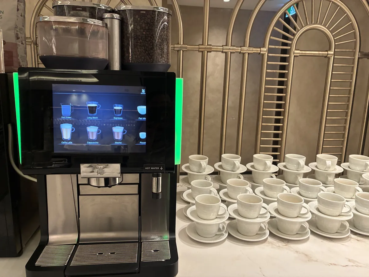 ラウンジのセルフサービスのコーヒーマシンと積み上げられたカップ&ソーサー