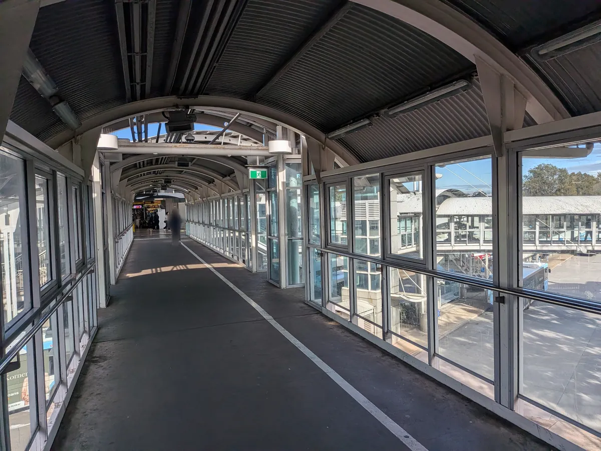 ブラックタウン駅とバスターミナルをつなぐ屋根つきの連絡通路。ガラス張りの壁の向こうにバス乗り場の屋根が見える