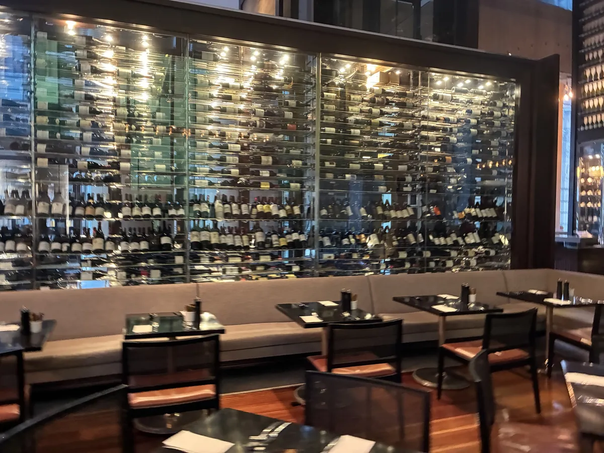 Glass Brasserieの店内。壁一面の3層ワインタワーとテーブル席