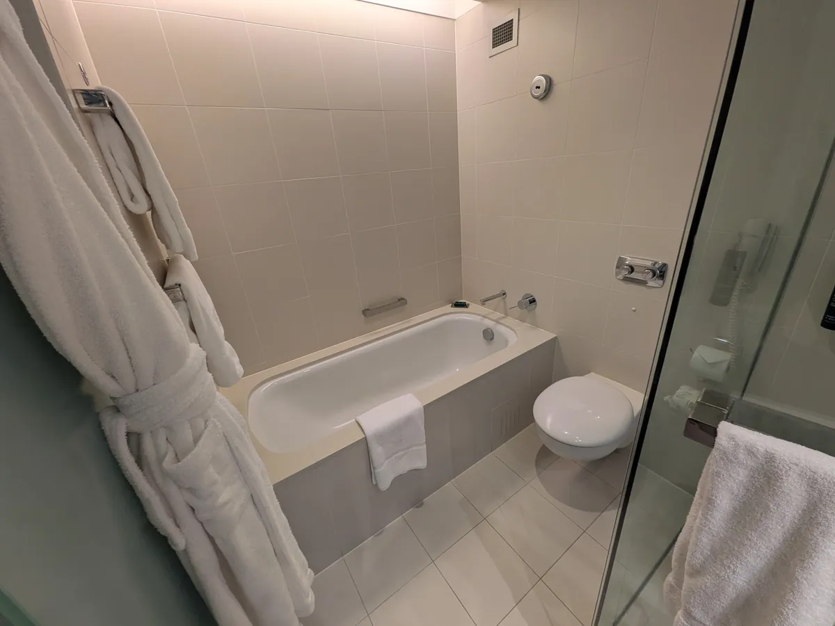 バスルーム。バスタブとトイレが横並びで、右手にガラス張りのシャワーブース