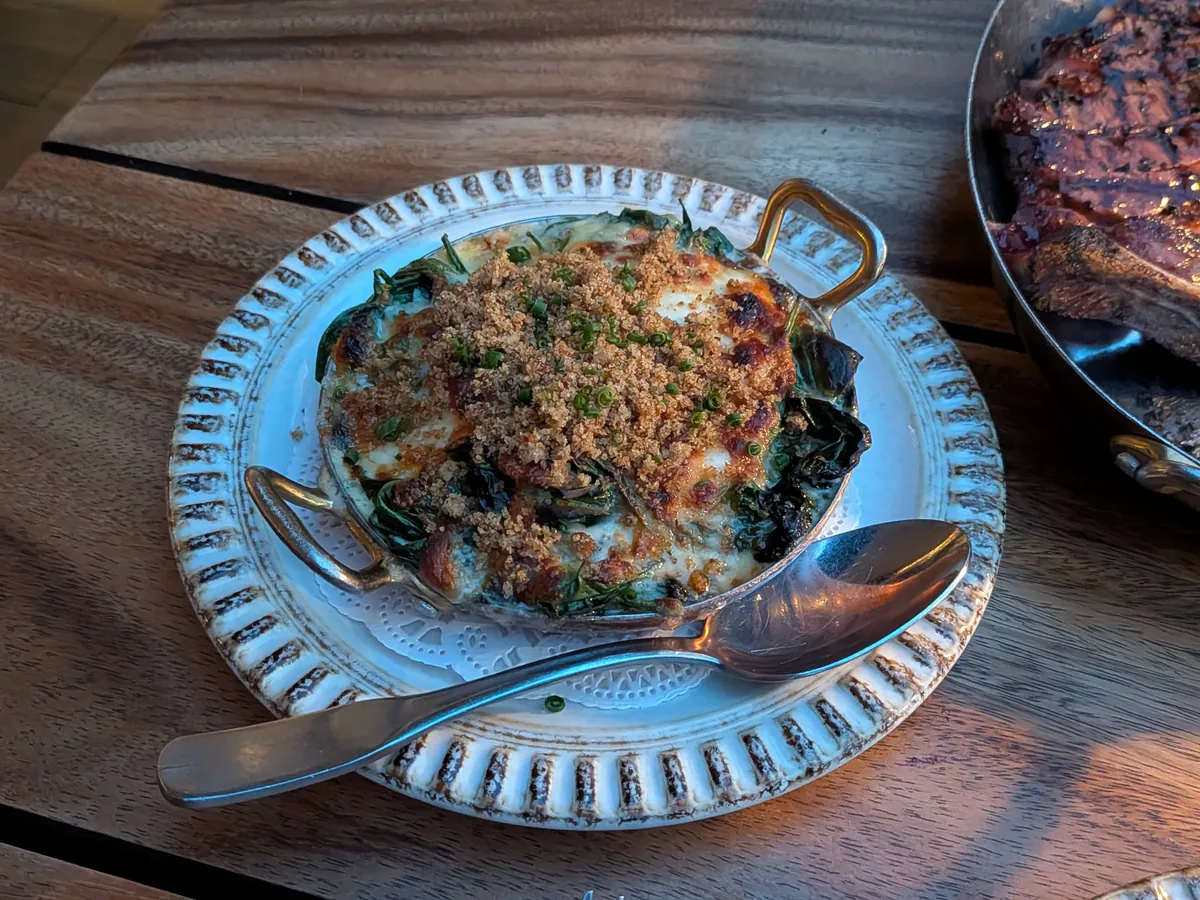 ほうれん草のグラタン。パン粉をふって焼き上げられ、耳付きの器で提供されている