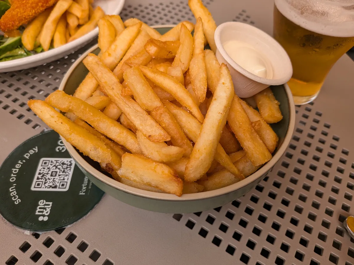 アイオリを添えたチップスのボウルとビールのグラス。手前にme&uのQRコード付きテーブル円盤が置かれている