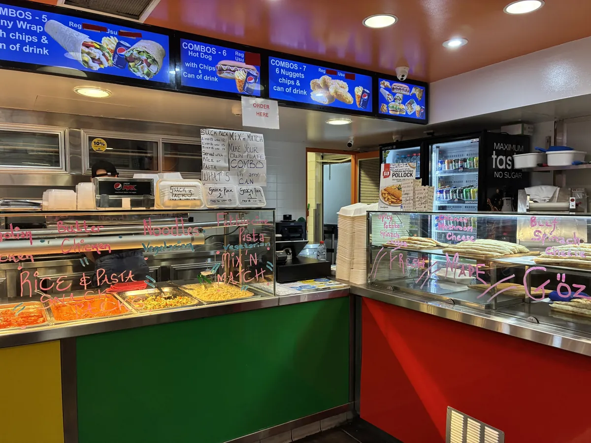 シドニー大学ウェントワース棟のケバブ店のカウンター。頭上のモニターにCOMBOSのセットメニューが並び、ガラスにはピンクの手書き文字でRICE & PASTAやMIX'N MATCHと書かれている