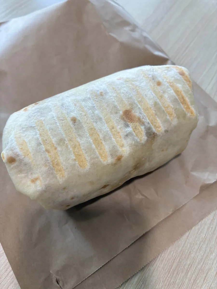 紙に包まれた押し焼きのパニーニ。表面に鉄板の焼き目がしっかり付いている