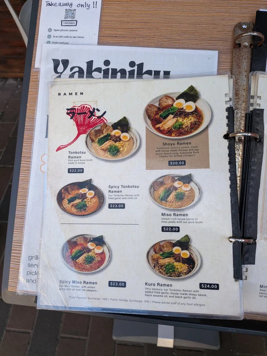 キャンパス周辺の日本料理店のラーメンメニュー。とんこつ、醤油、味噌、黒ラーメンなどの写真と価格が並ぶ