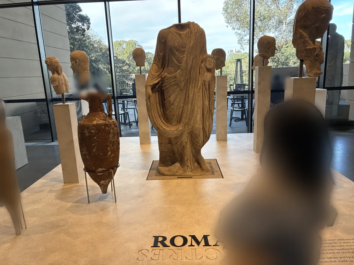 チャウ・チャク・ウィング博物館のローマ展示室。頭部のない大理石の胴体像と、台座に載った複数の頭部彫刻、貝の付いたアンフォラが並ぶ