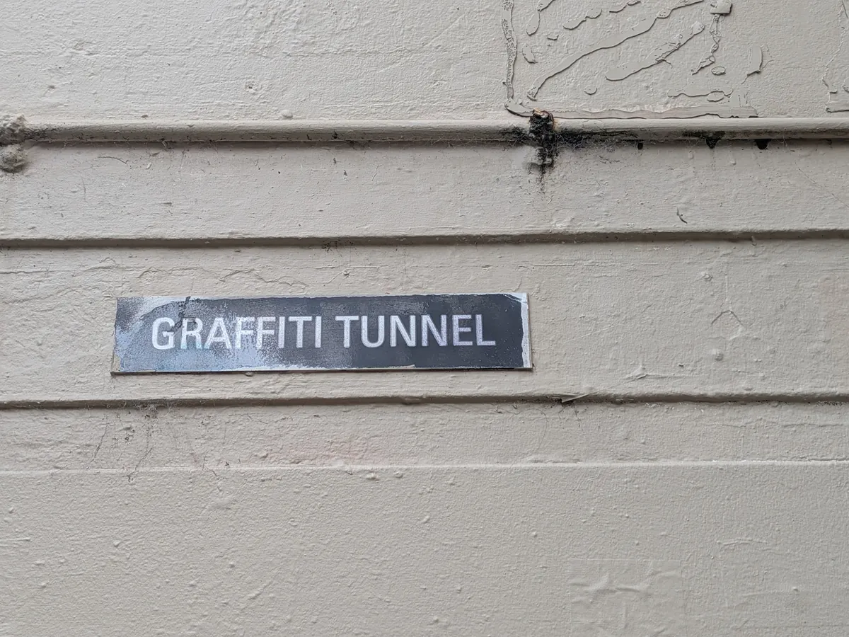 クリーム色の壁に取り付けられた「GRAFFITI TUNNEL」と書かれた黒いプレート
