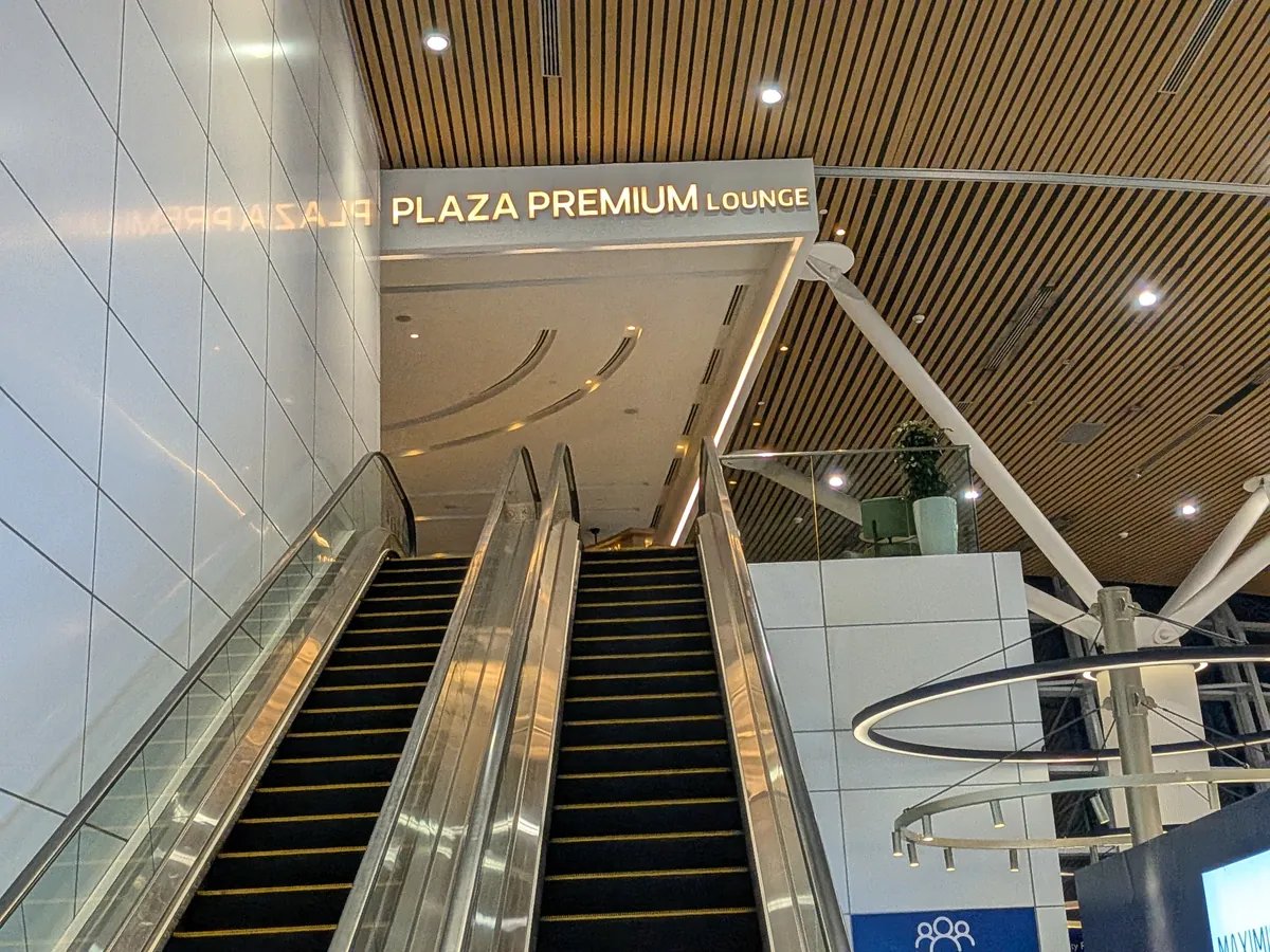 PLAZA PREMIUM LOUNGEの金文字サインと、ラウンジへ上がるエスカレーター