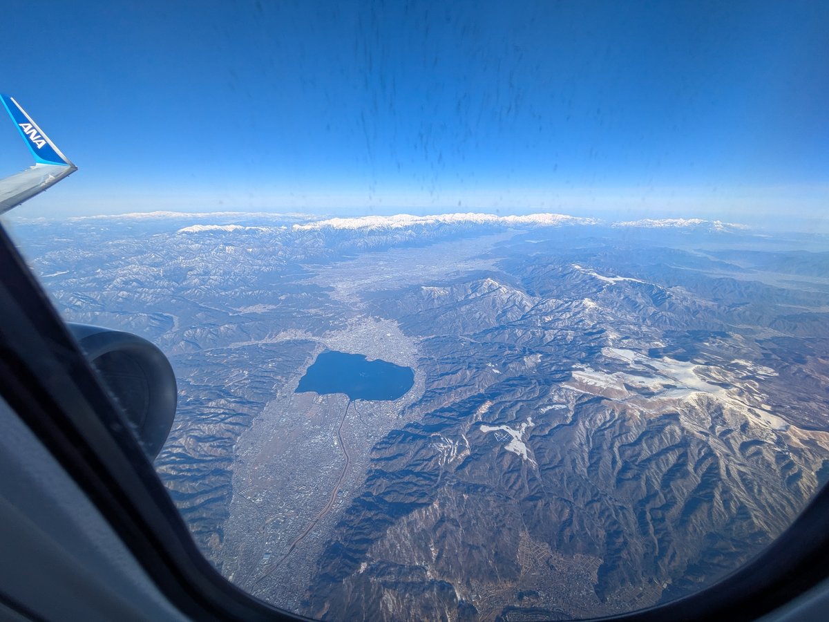 ANA機内から見た、手前に諏訪湖、奥に雪山が連なる日本の冬の景色