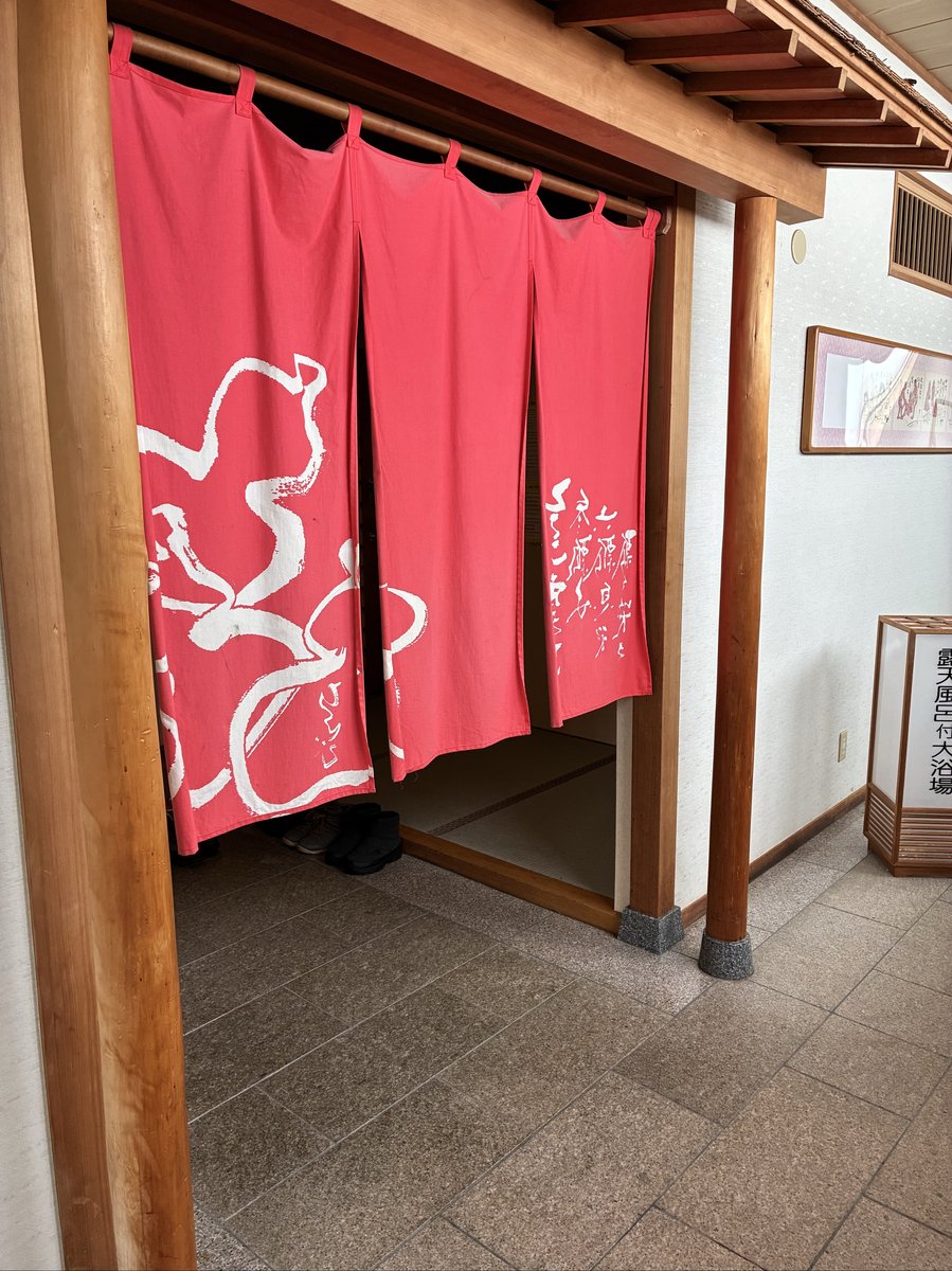 館内にある大浴場への入り口。赤地に白い文字で「大浴場」と書かれた暖簾がかかり、その奥には脱ぎ揃えられた靴が見える。