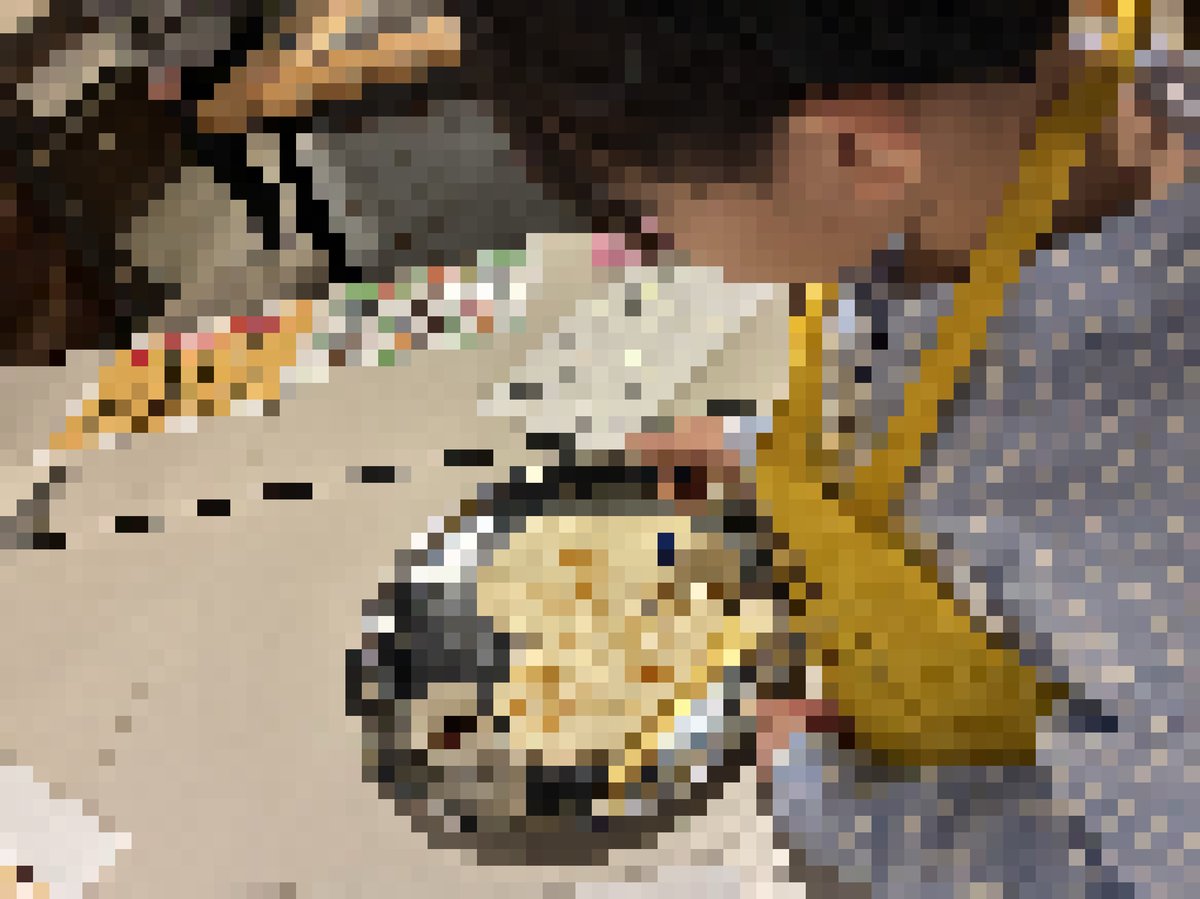 集中してハート型のせんべいに絵筆で醤油の絵付けをするメイの手元