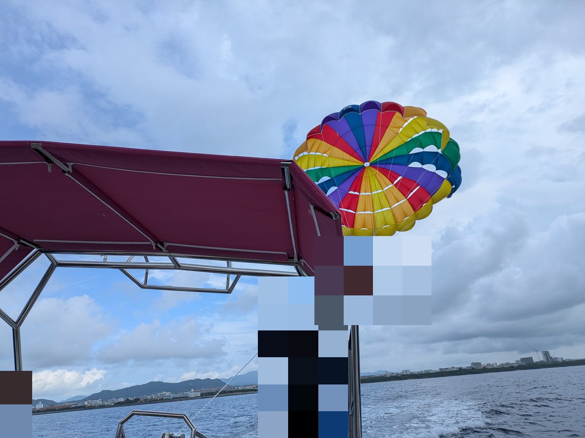 沖縄の海でパラセーリング。ボートから空へ舞い上がるカラフルなパラシュート