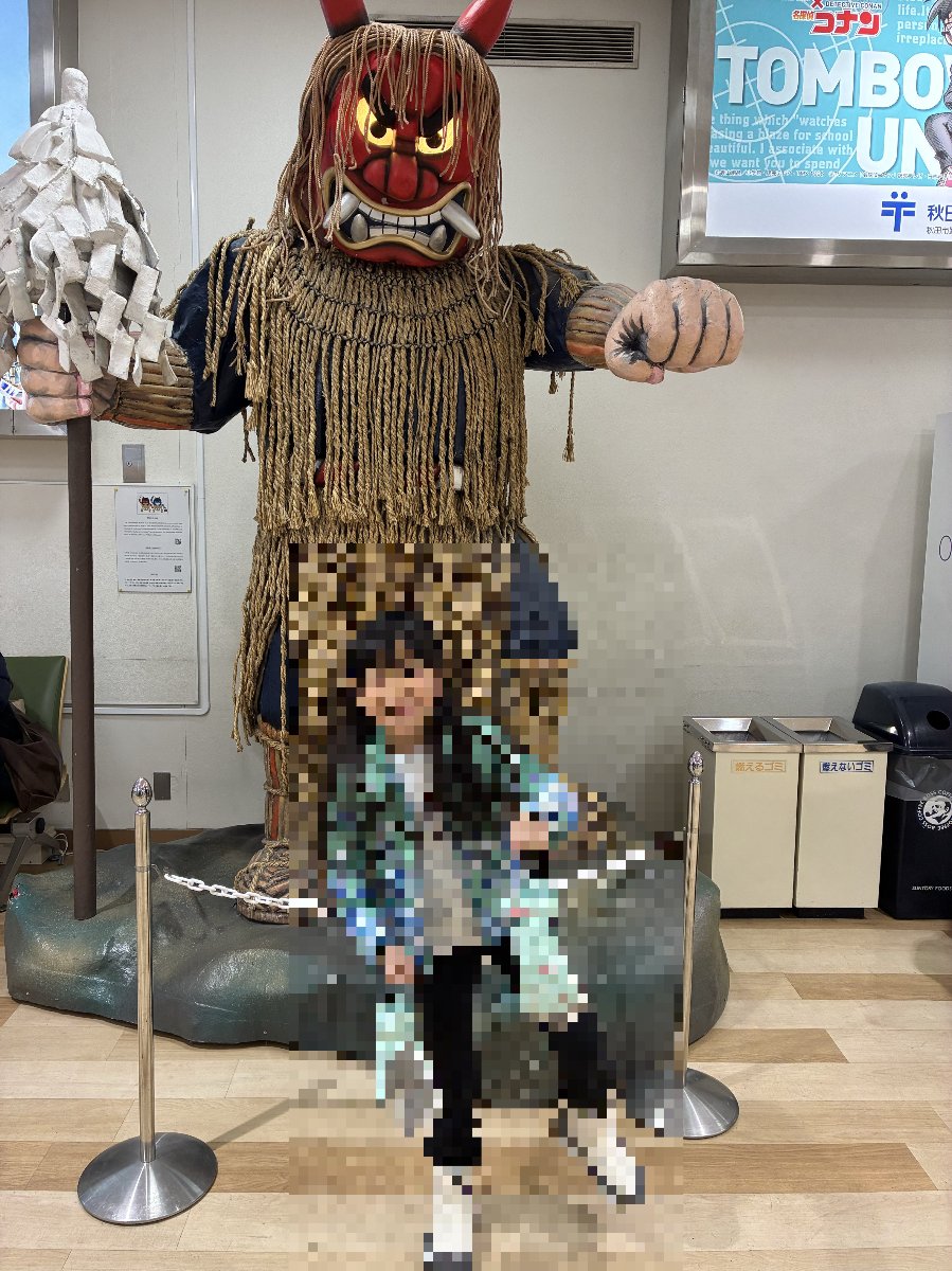 秋田空港のなまはげ像の前でポーズを取るメイ