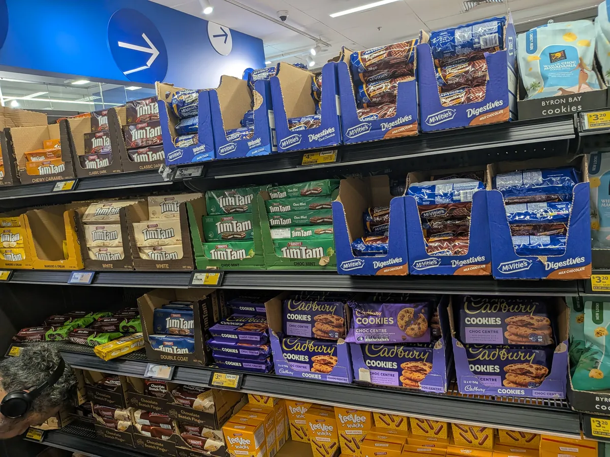 ウールワースのチョコレート・ビスケット売り場に並ぶティムタムやキャドバリーの棚